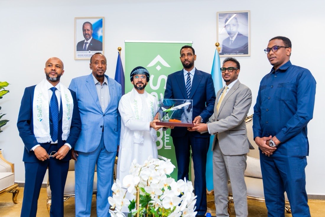 Guests at a formal reception in Mogadishu, two of them holding a model SalamAir aircraft in a display case