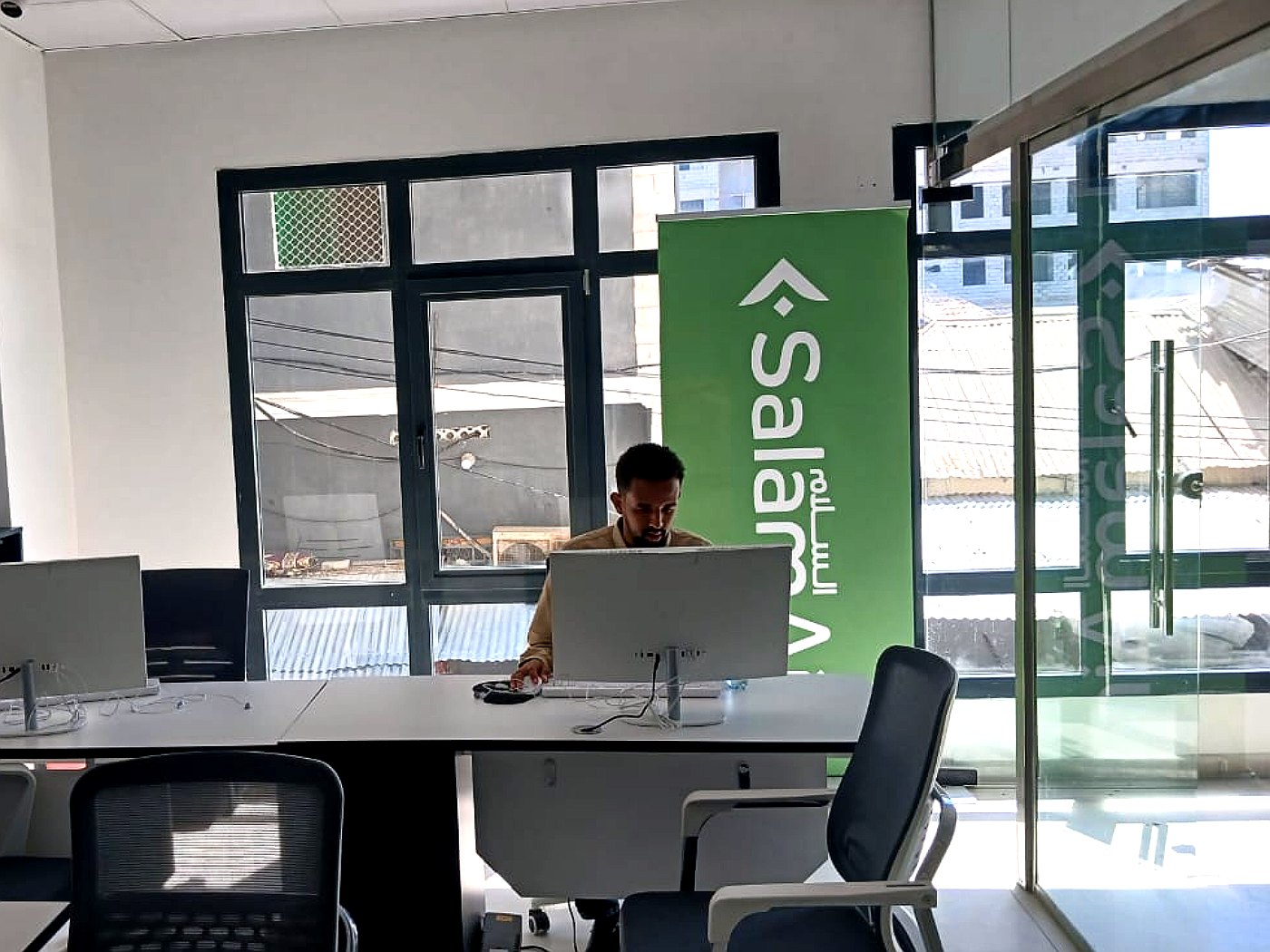 An Ibra Travel agent at the booking desk in the Mogadishu office, beside a SalamAir banner